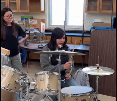 Students practicing playing the drums in classroom.