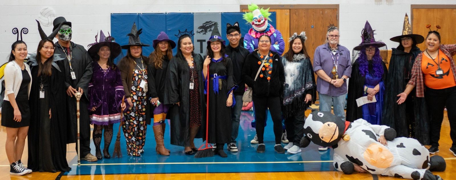 School staff dressed in creative Halloween costumes, showcasing their festive spirit with big smiles and playful poses.